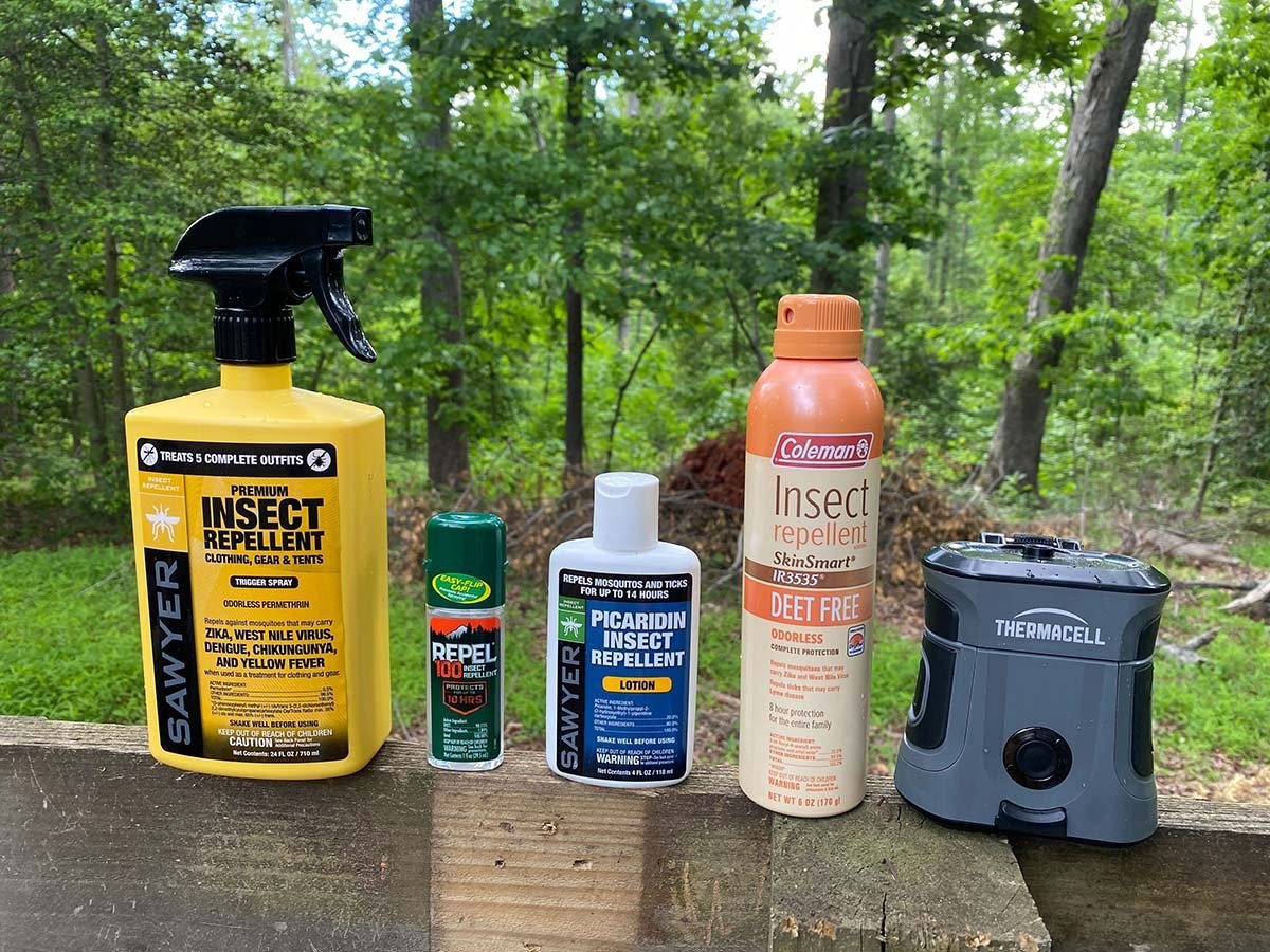 A collection of effective mosquito repellent gear laid out on a forest hiking trail.