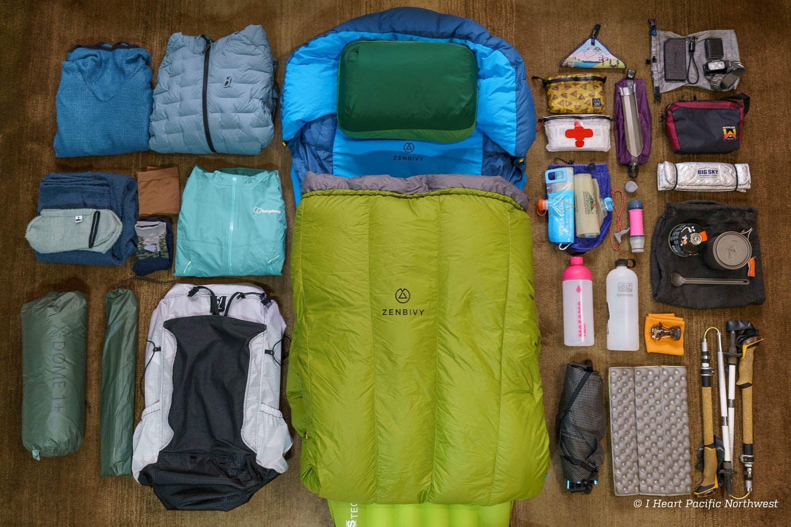 A collection of essential ultralight hiking gear arranged neatly on a forest floor.