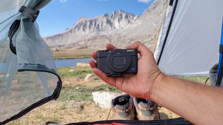 A compact digital camera resting on a mountain rock while hiking outdoors.