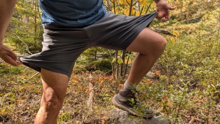 A durable nylon hiking belt rests on a log near a forest trail.