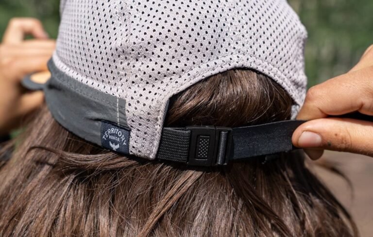 A green hiking cap resting on a mountain rock on a sunny trail.