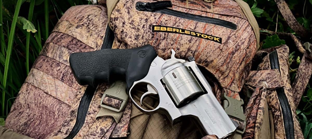 Handgun and hiking gear on a log in a forest trail