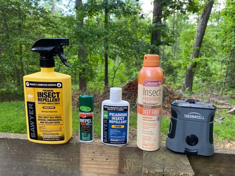 Hiking gear and insect repellent spray resting on a mossy rock in the woods.