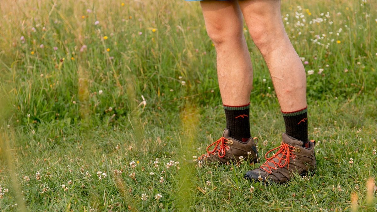 Lightweight merino wool hiking socks resting on a rock near a forest trail.