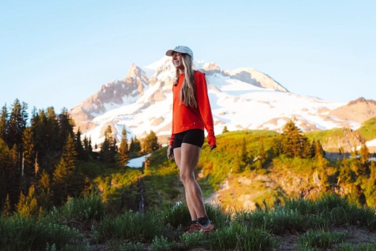 A lightweight sun hoody draped over a wooden post on a mountain trail.