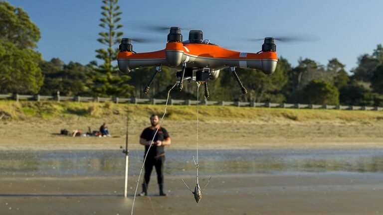 A modern fishing drone hovers over calm ocean water to drop bait.