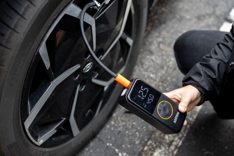 Modern portable tire inflator sitting on the ground beside a car tire.