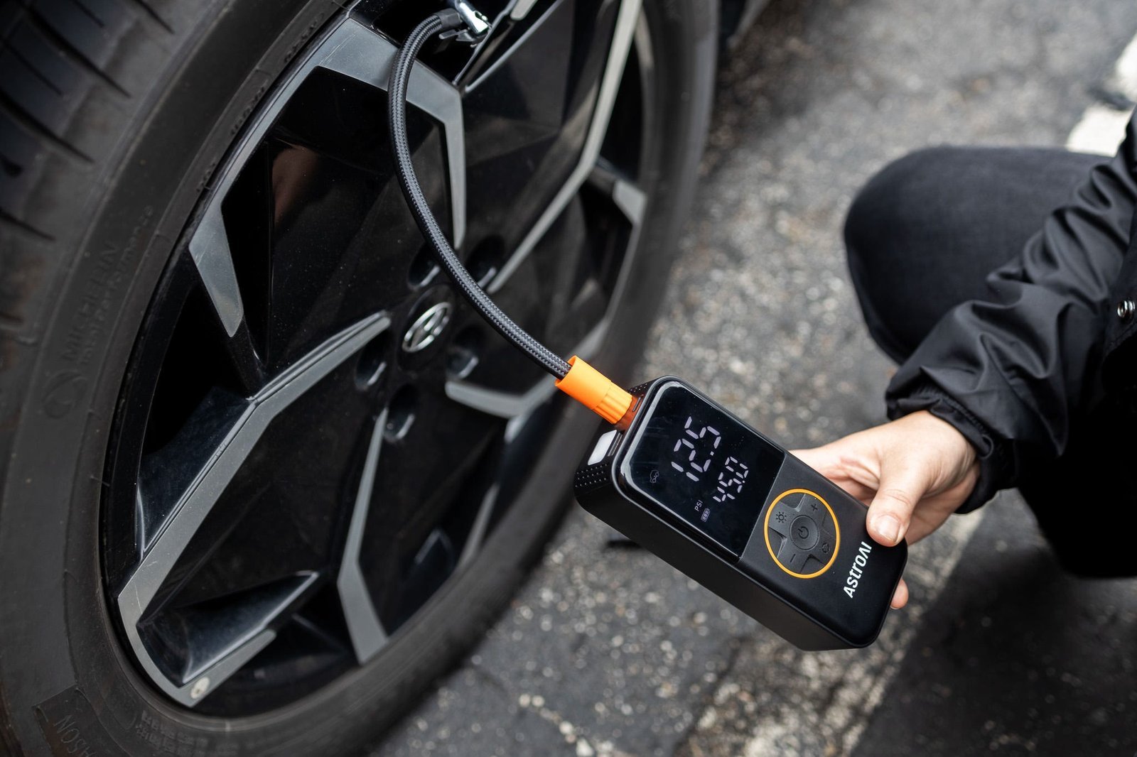 Modern portable tire inflator sitting on the ground beside a car tire.