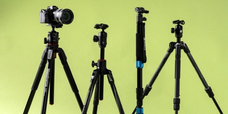 A professional carbon fiber camera tripod stands on a rugged mountain ridge.