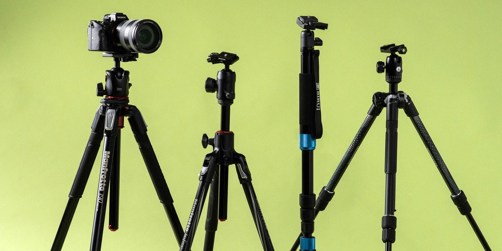 A professional carbon fiber camera tripod stands on a rugged mountain ridge.