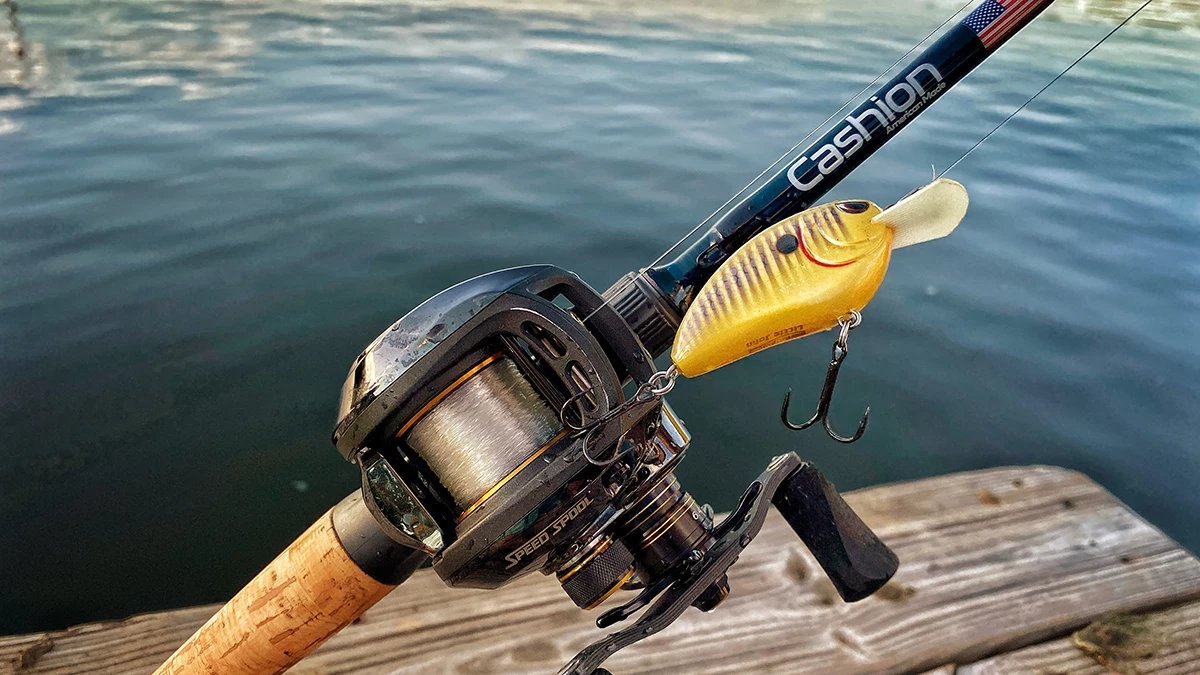 A professional fishing rod and crankbait lure resting on a wooden dock.