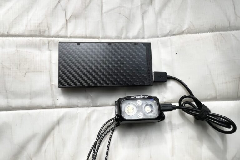 A rugged power bank for hiking resting on a mountain trail rock.