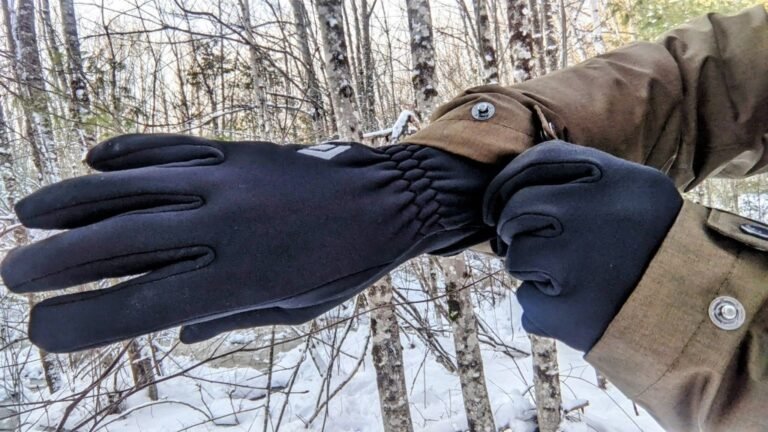 Technical hiking gloves resting on a frosted mountain peak during a winter trek.