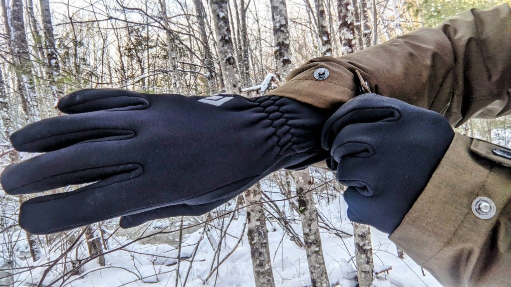 Technical hiking gloves resting on a frosted mountain peak during a winter trek.