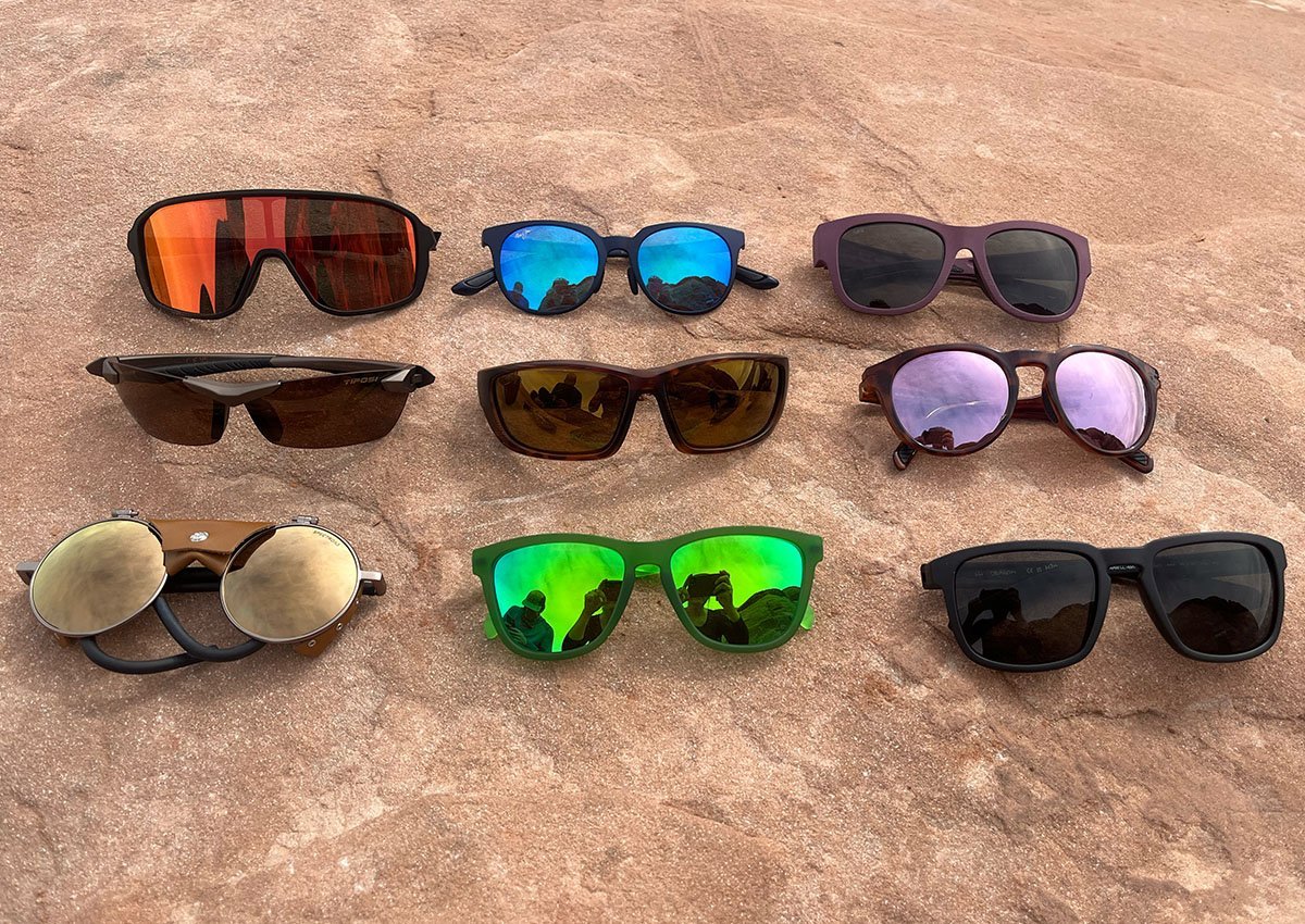 Wraparound polarized hiking sunglasses resting on a rock along a forest trail.